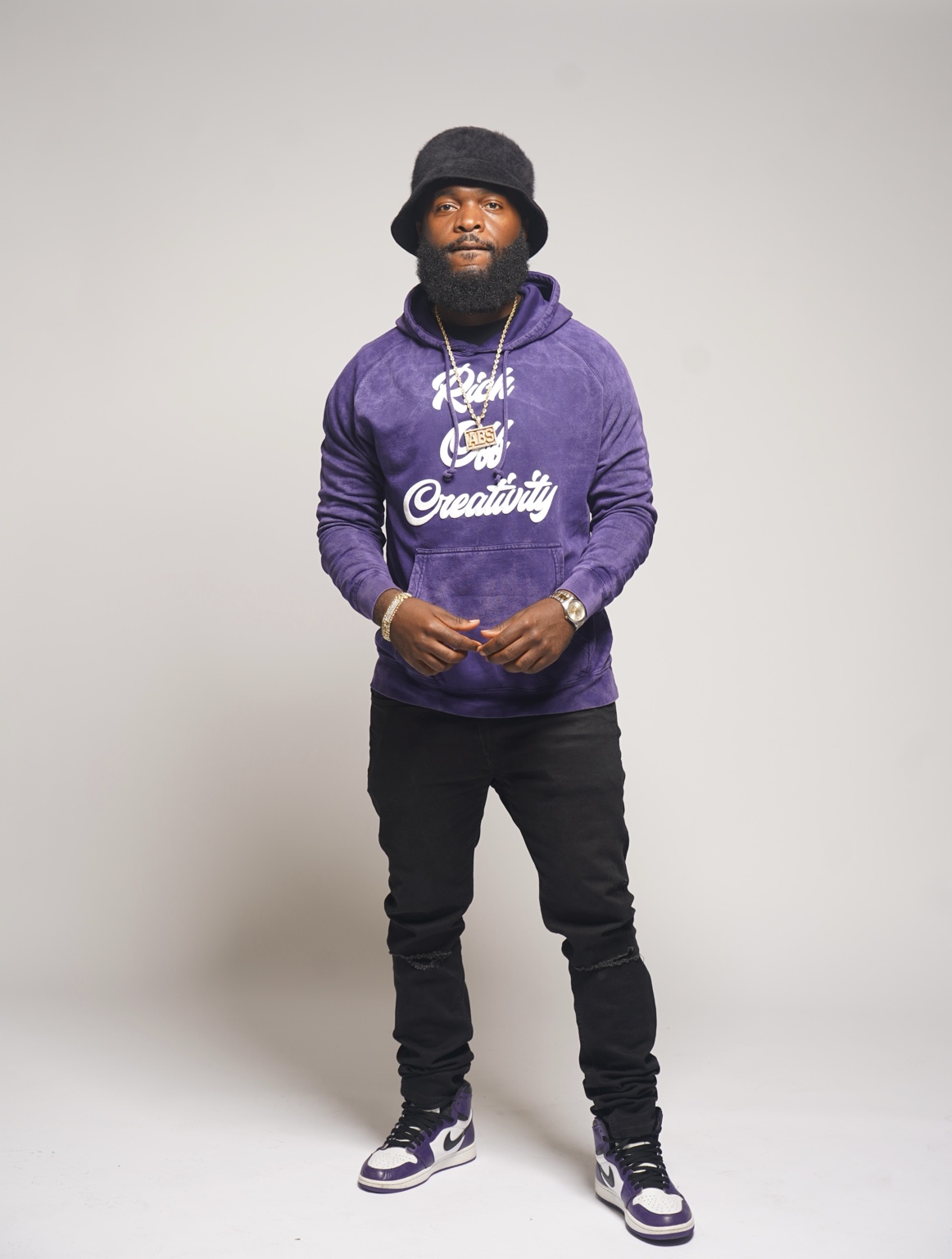 Man wearing the purple Rich Off Creativity hoodie