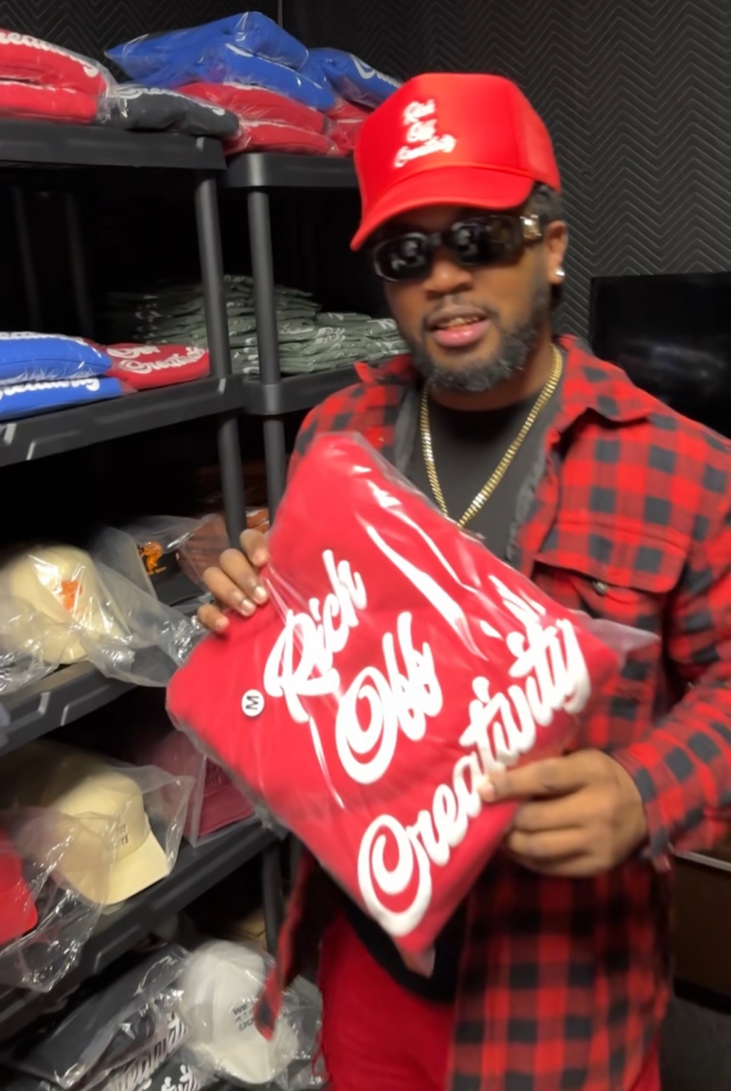 Creative holding a packaged red Rich Off Creativity hoodie inside the Lu.C. stockroom