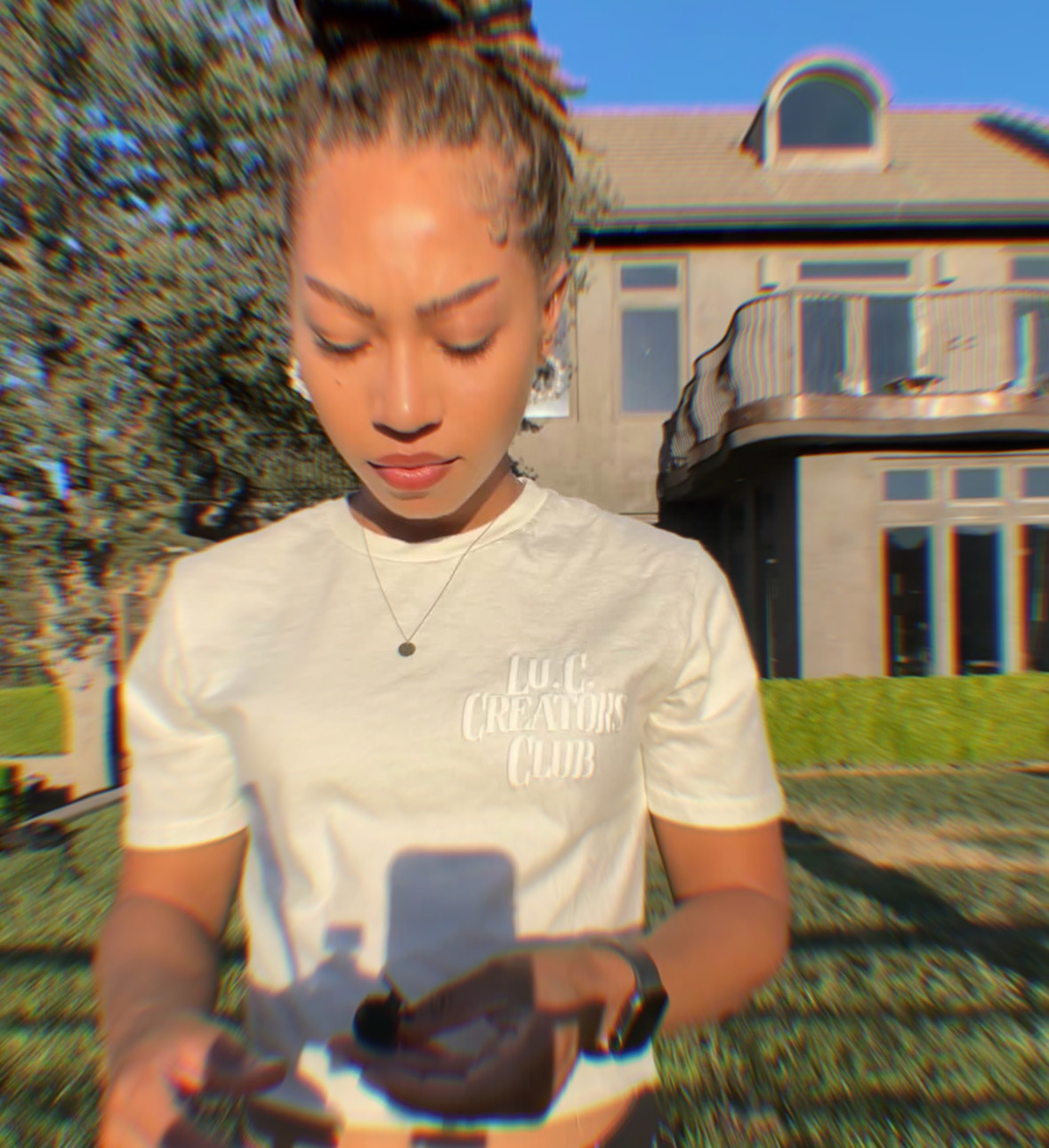 Woman wearing a white Lu.C. Creators Club shirt outdoors