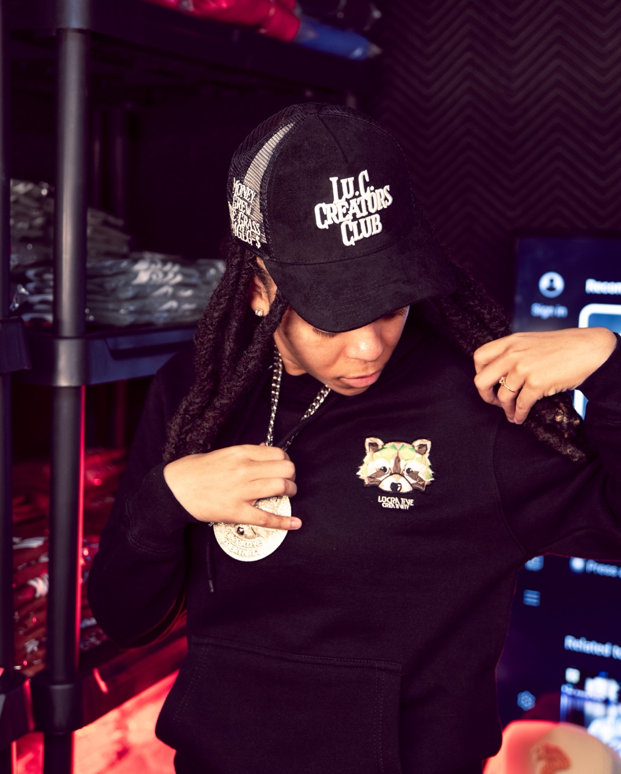 Creative wearing a Lu.C. Creators Club cap and Lucrative Creativity raccoon hoodie